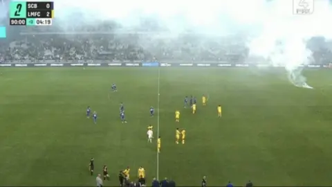 2-0 dẫn đầu trận then chốt thăng hạng Le Mans nhưng trận đấu bị gián đoạn do fan đối thủ ném bom khói